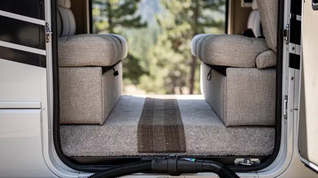 The open side door of an RV with shampooed dinette seats and floor runner